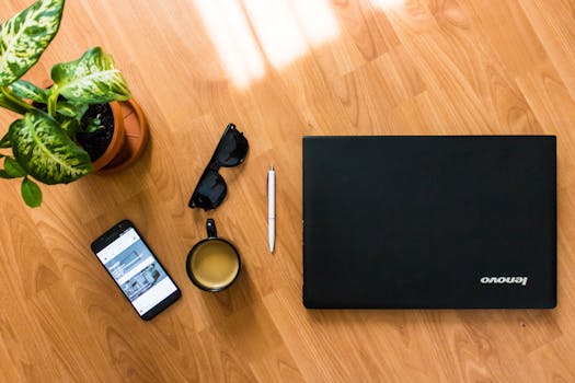 A flat lay of a desk with a laptop, coffee cup, smartphone, and plant, perfect for a modern office setting.